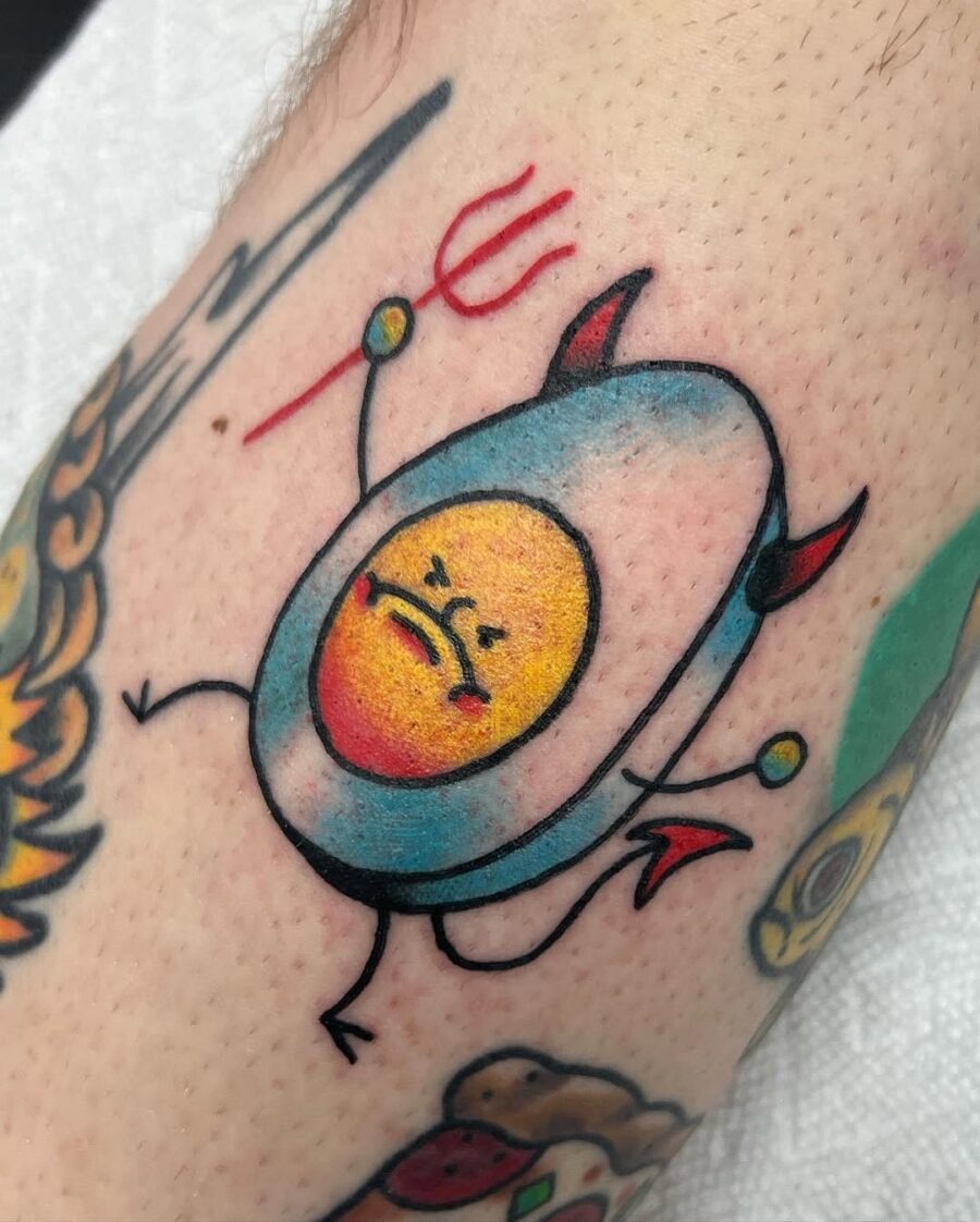 This tattoo features a quirky cartoon egg with a sassy expression and devilish horns.