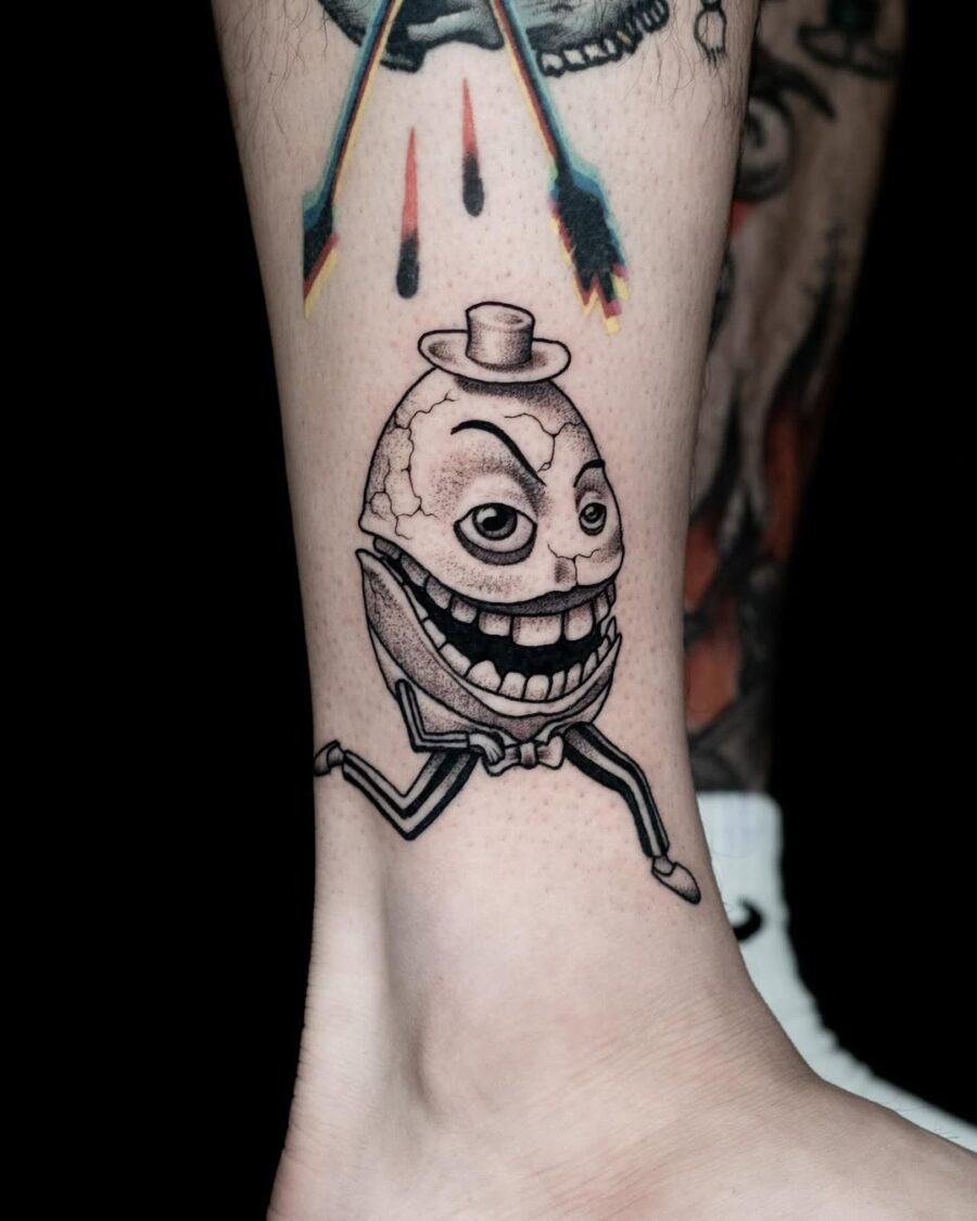 This quirky tattoo showcases an egg character sporting a top hat and a big grin.