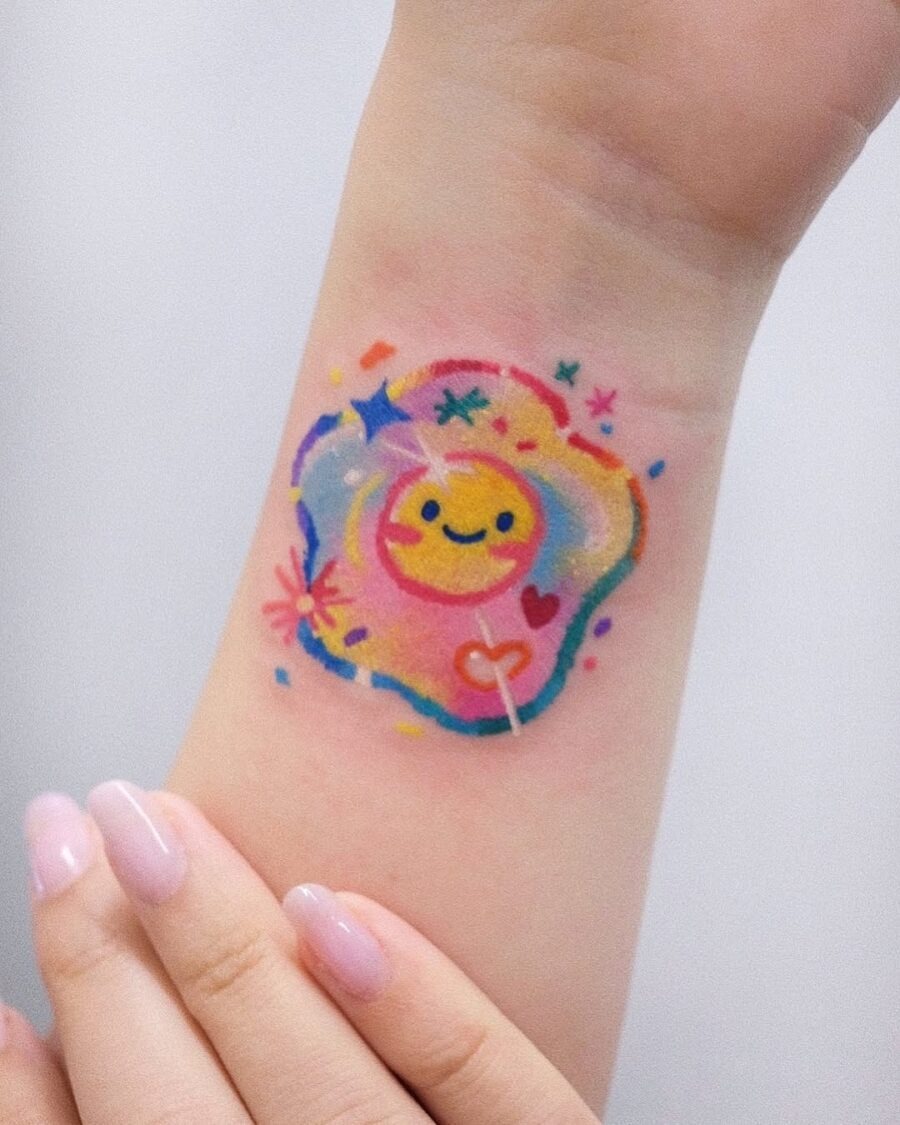 This egg tattoo features a cheerful smiley face nestled in a colorful, splashy design.