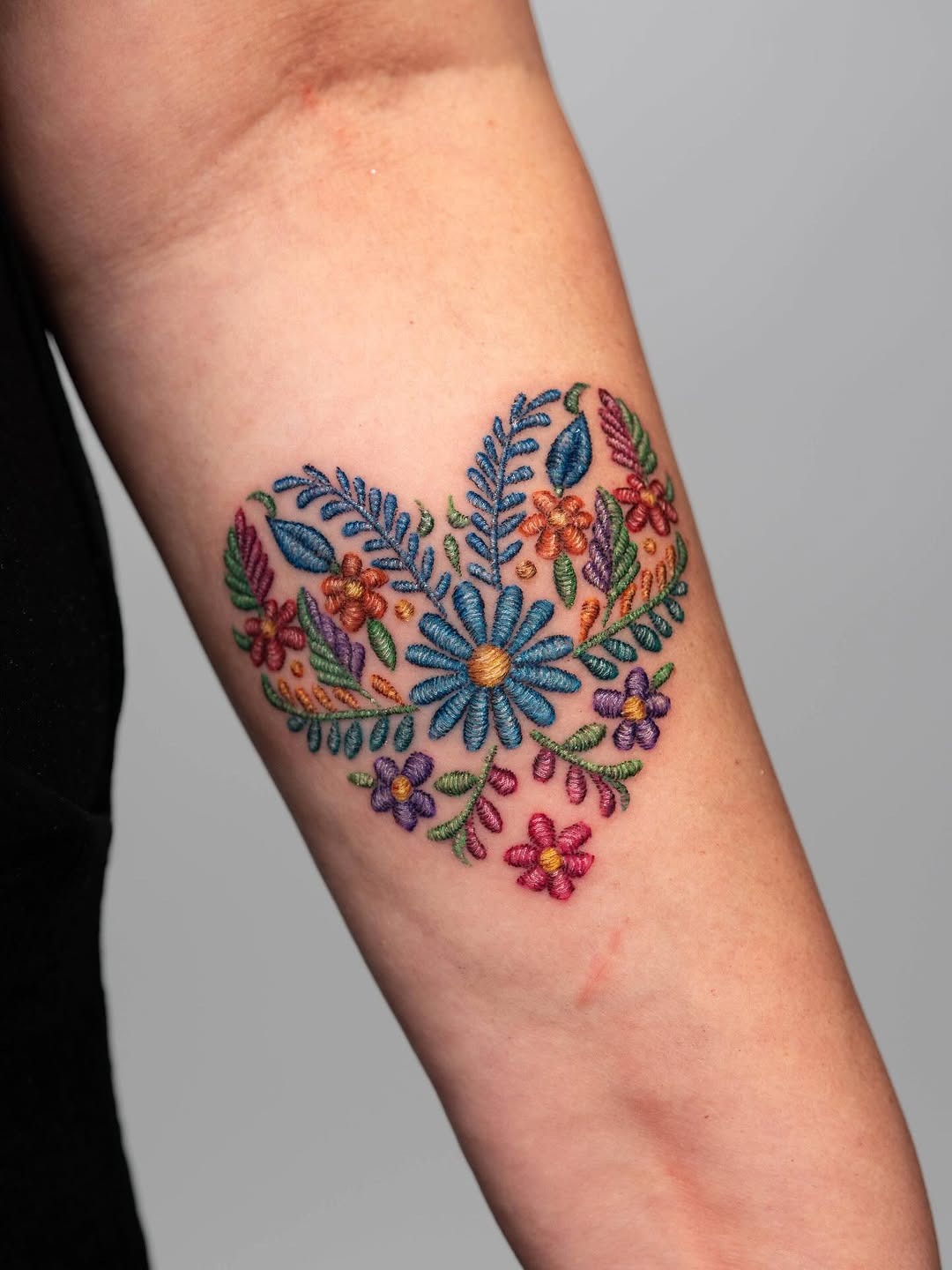 Colorful floral embroidery tattoo on forearm Tattoo Design