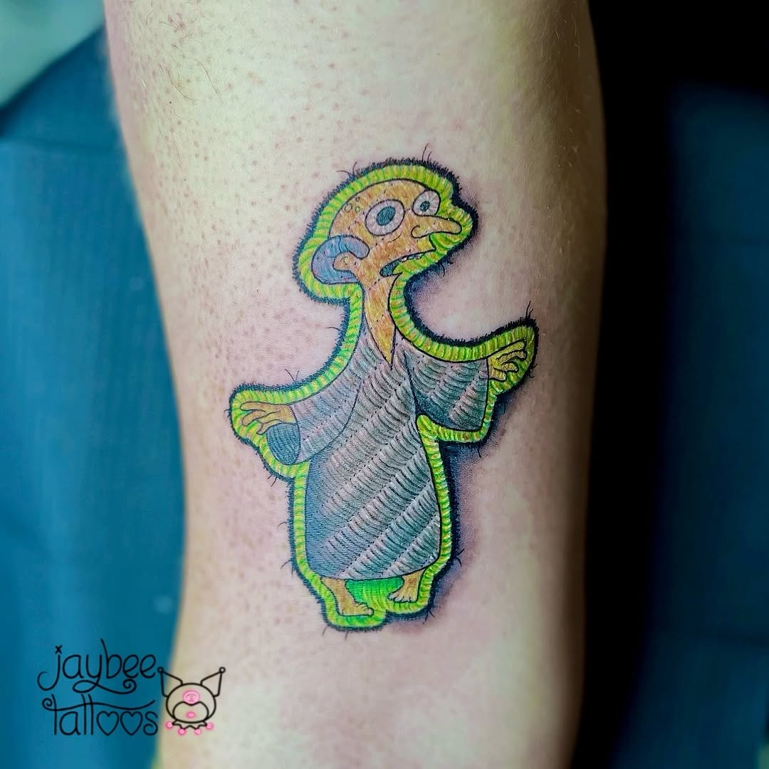 Playful embroidered character tattoo with vibrant hues Tattoo Design