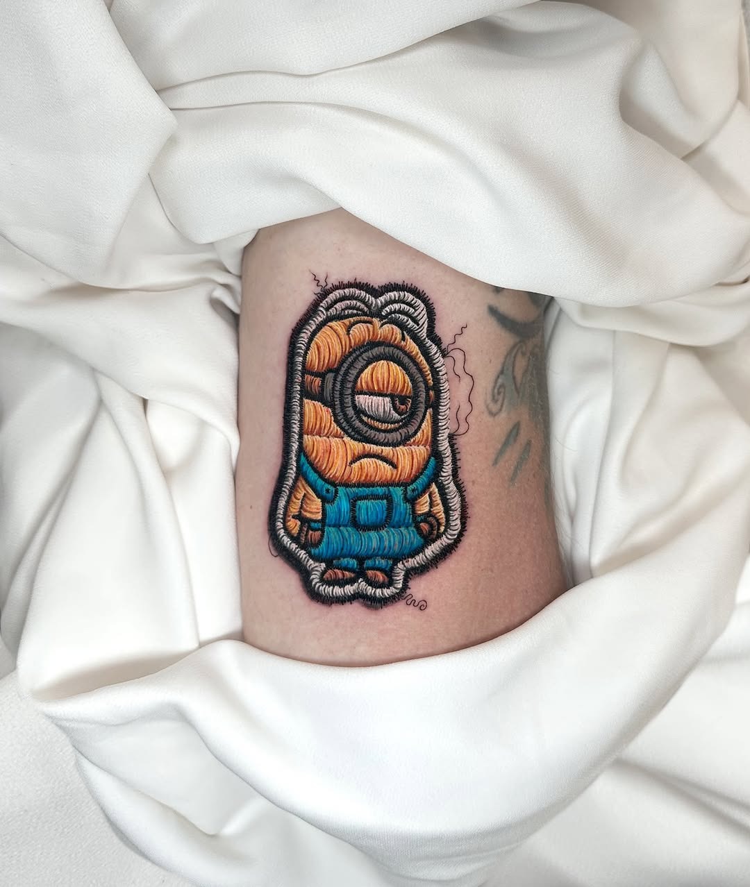 Whimsical minion-inspired embroidery tattoo design Tattoo Design