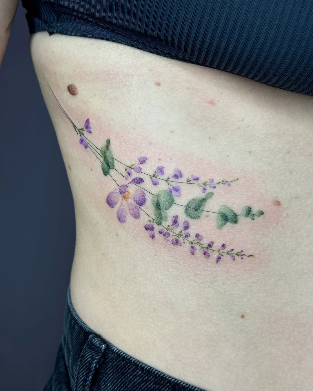 Delicate eucalyptus and floral rib tattoo design Tattoo Design