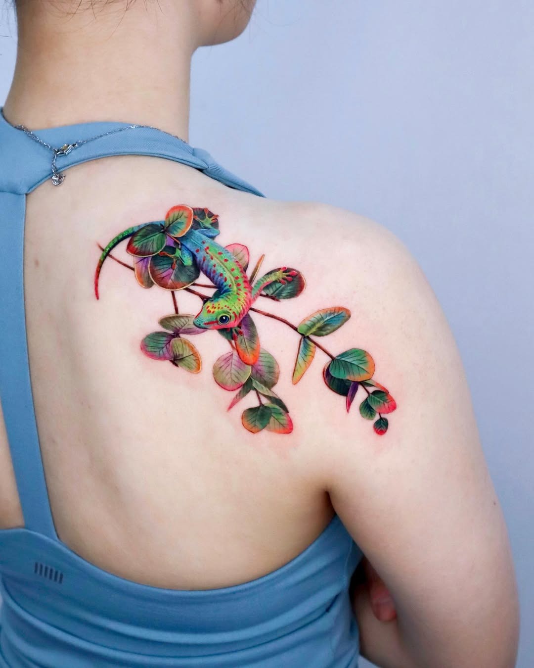 Vibrant eucalyptus tattoo with a lizard design Tattoo Design