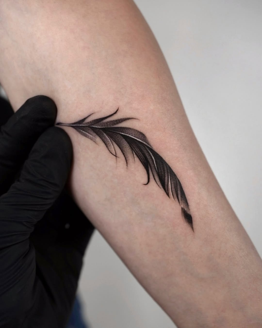 Elegant black feather tattoo design on arm Tattoo Design