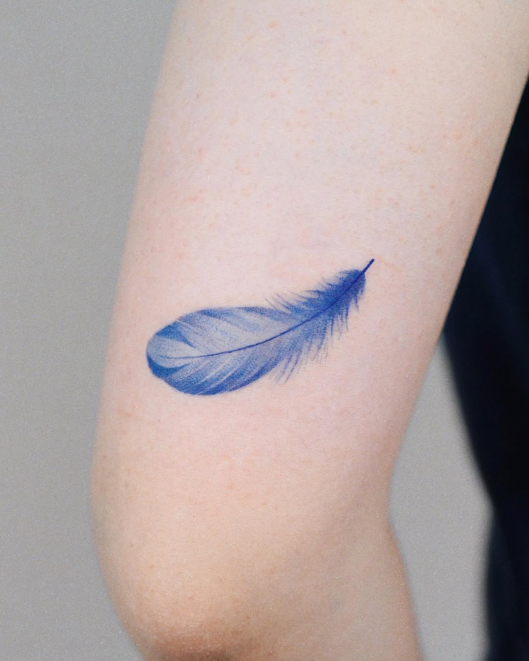 Elegant blue feather tattoo on the arm Tattoo Design