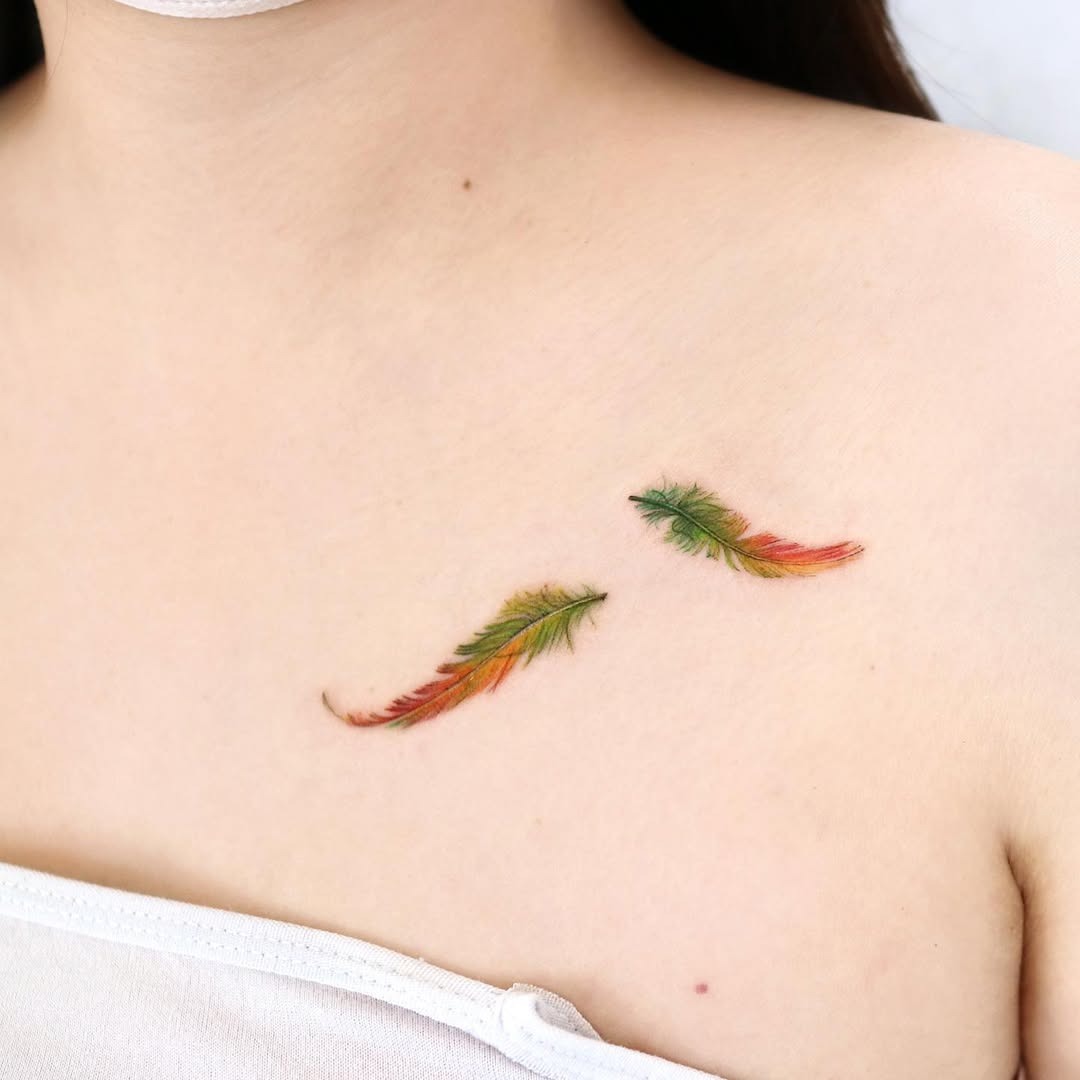 Vibrant feather tattoos on the collarbone area Tattoo Design
