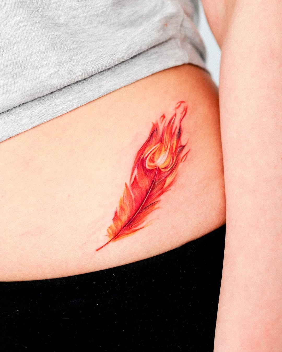 Vibrant Red Feather Tattoo with Flame Embellishments Tattoo Design