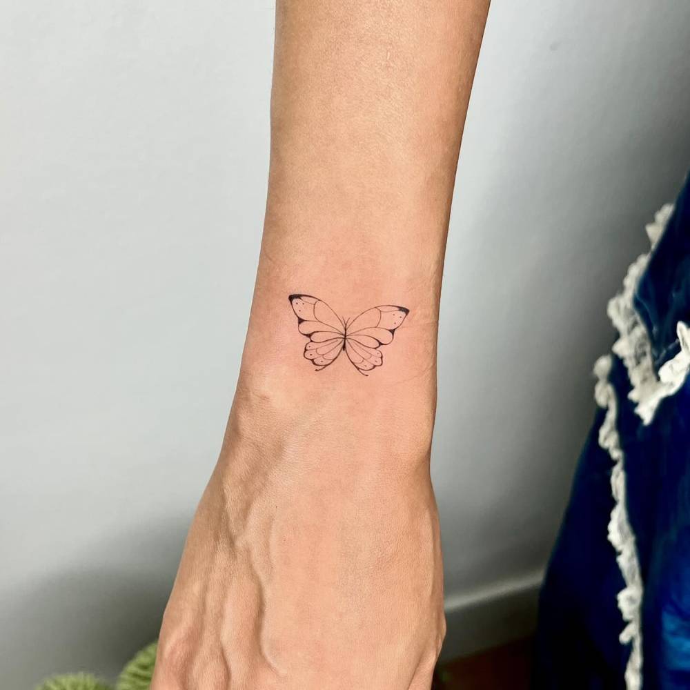 Small fine line butterfly tattoo on the wrist