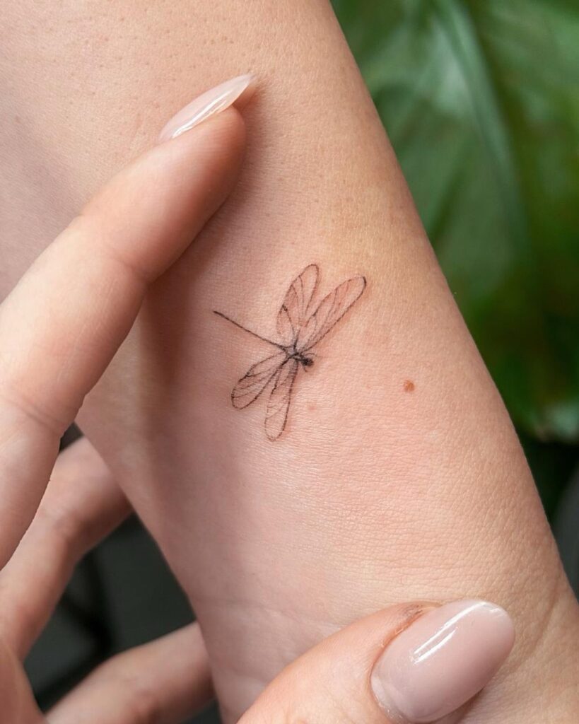Fine line dragonfly tattoo on the wrist