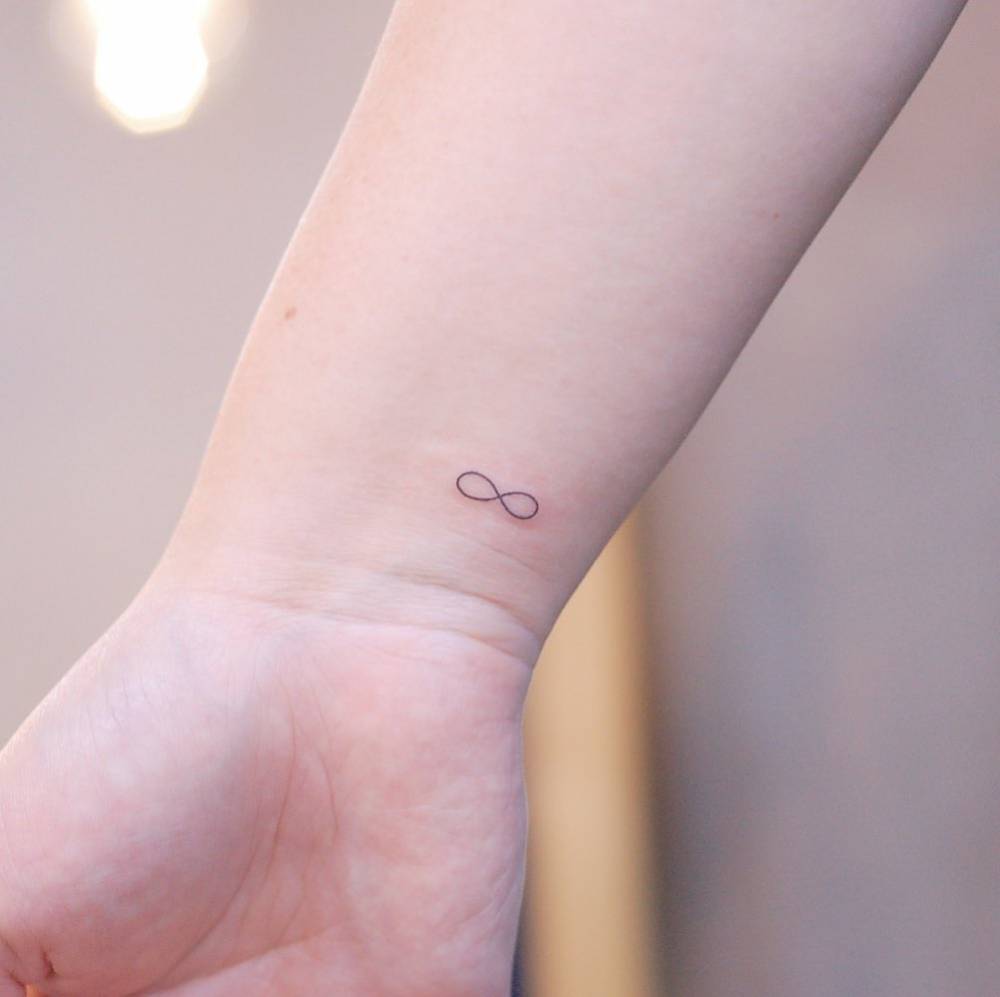 Minimal fine line infinity symbol tattoo on the inner wrist