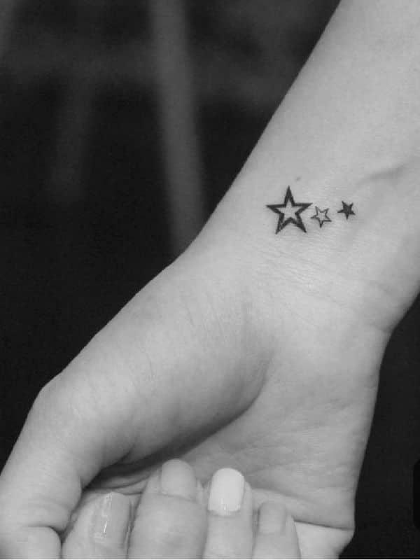 Line of three tiny star tattoos on the wrist