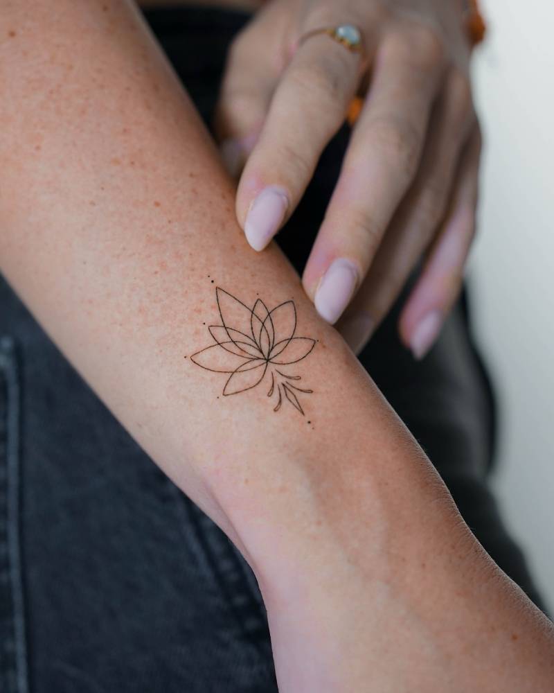 Delicate fine line lotus tattoo on the inner wrist