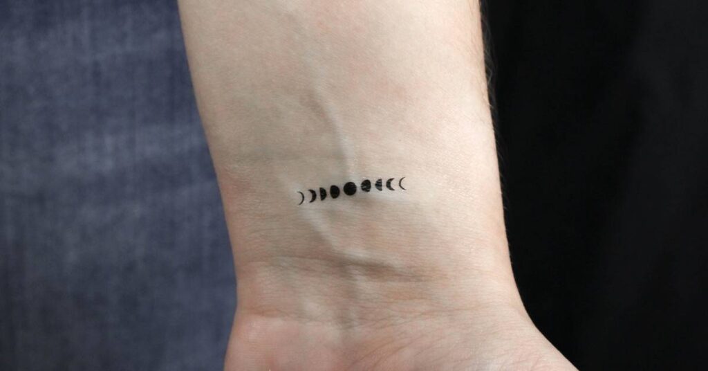 Row of tiny moon phases tattoo across the wrist