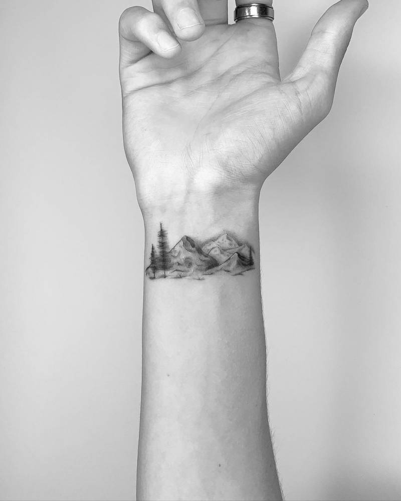 Fine line mountain range tattoo around the wrist