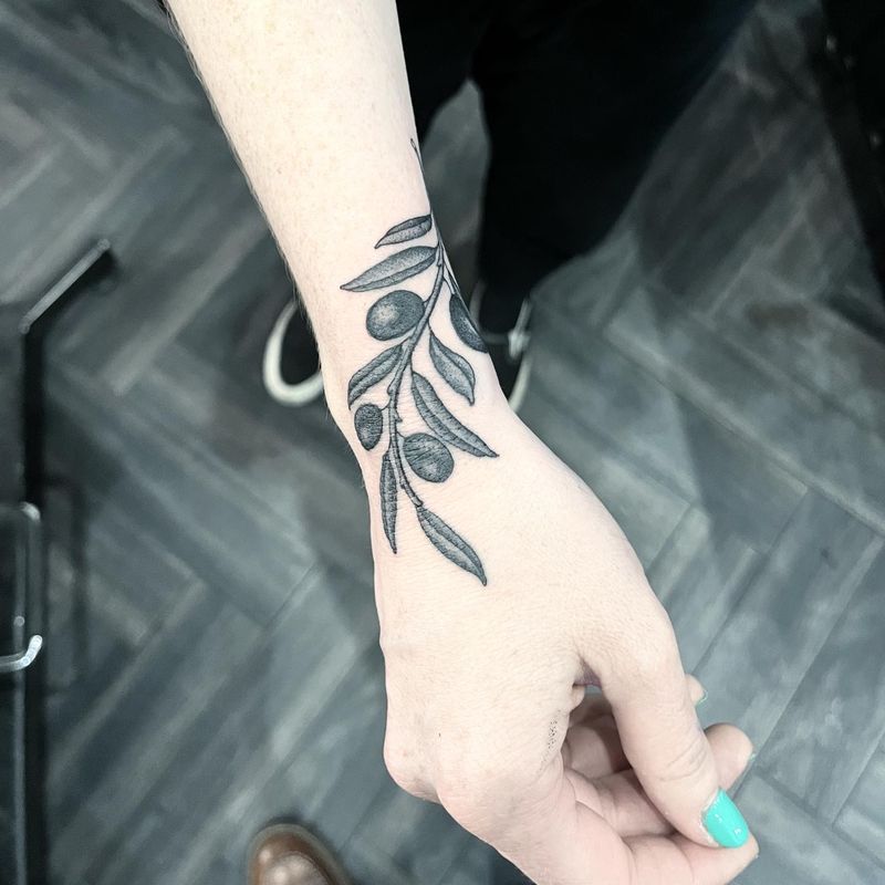 Tiny olive branch tattoo on the wrist and hand