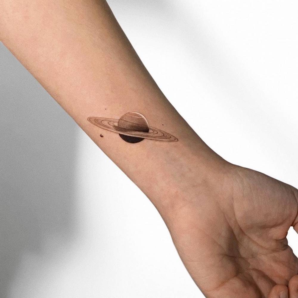 Tiny ringed planet tattoo on the wrist