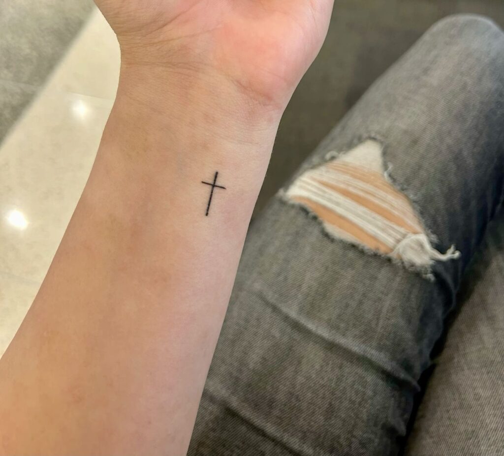 Small fine line cross tattoo on the inner wrist