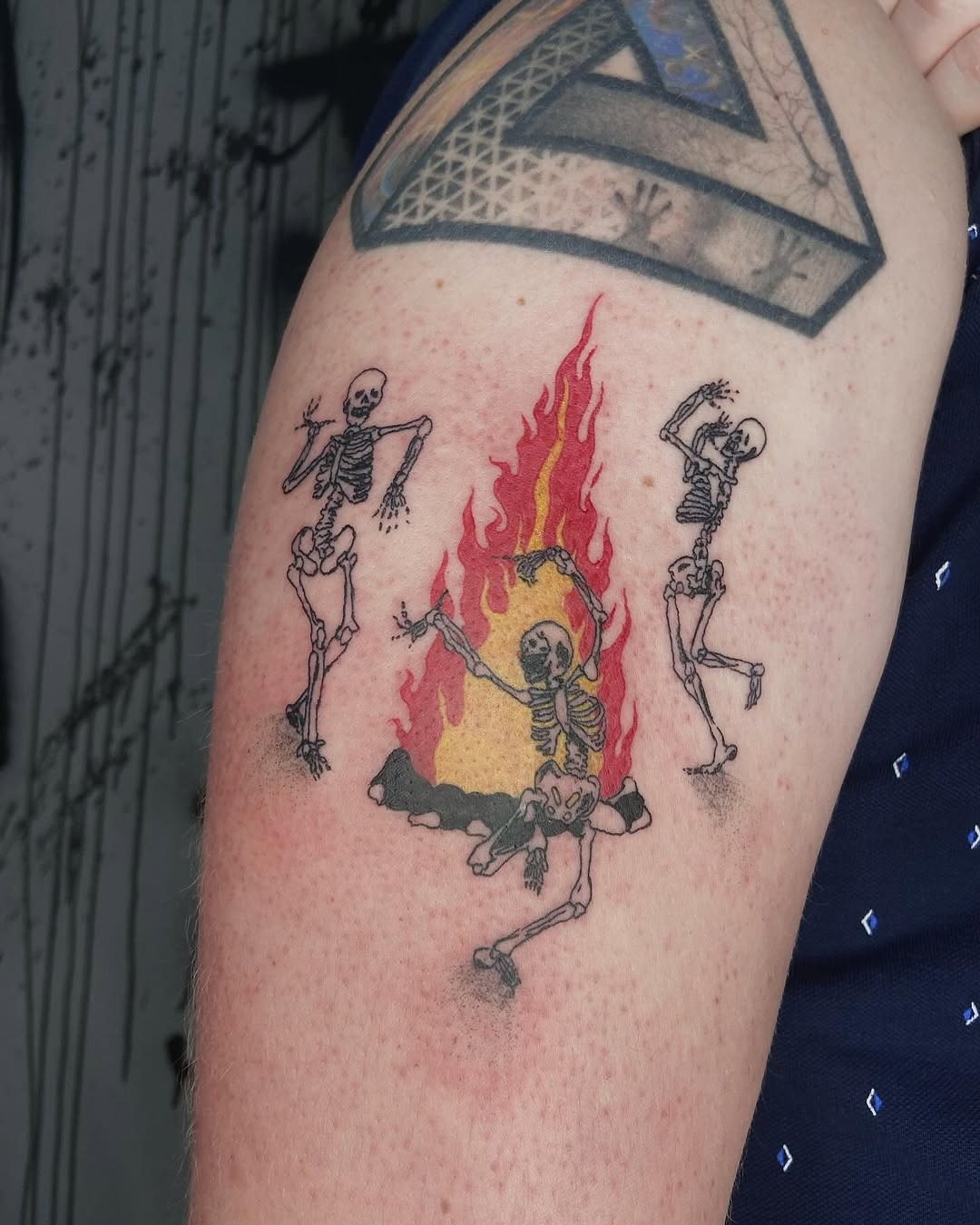 Energetic skeletons celebrate around vibrant flames. Tattoo Design