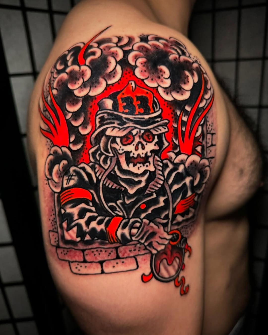 This tattoo showcases a striking image of a skull-clad firefighter amidst dramatic red flames and smoke.
