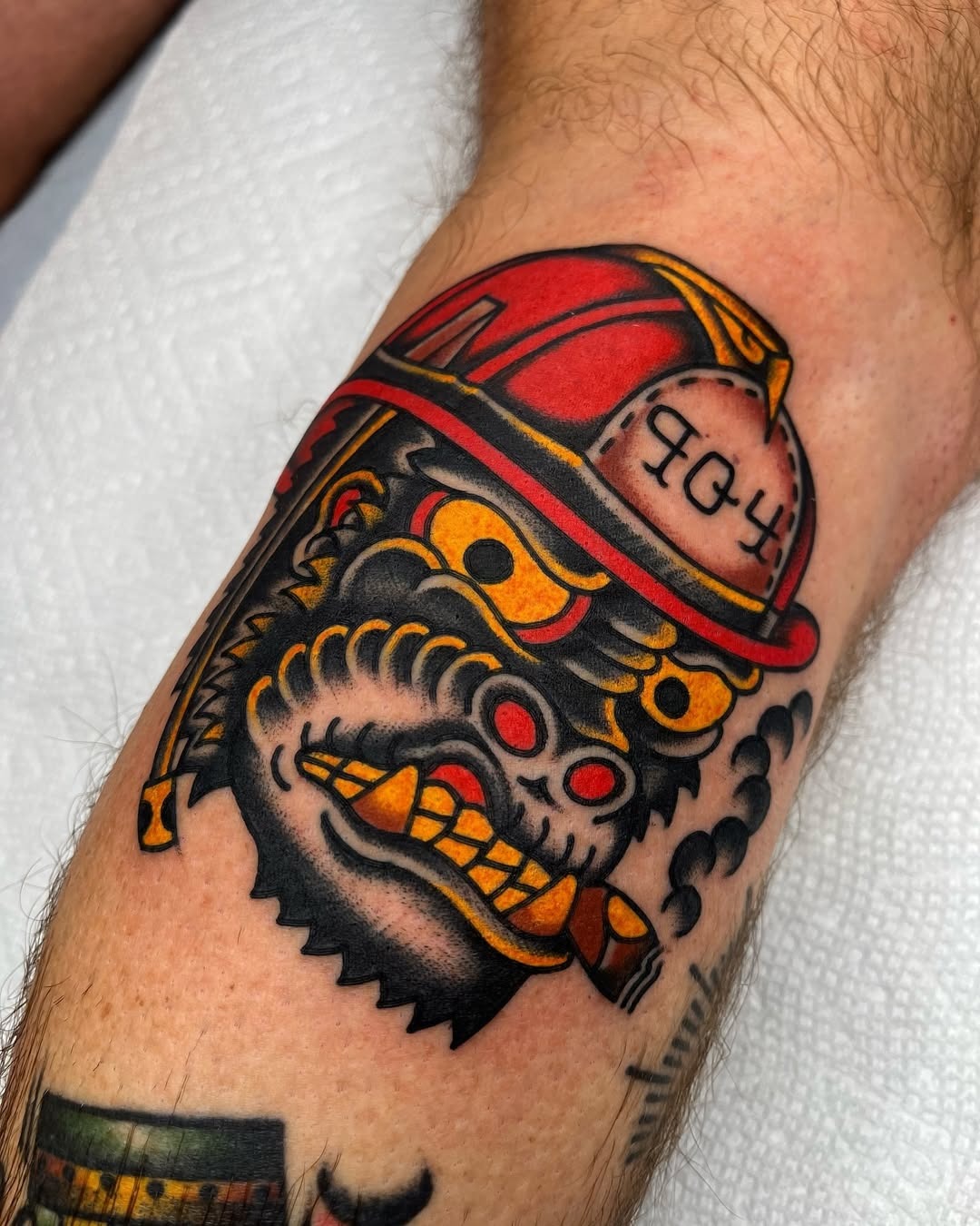 This tattoo features a fierce design of a firefighter's helmet combined with vivid colors and striking imagery.