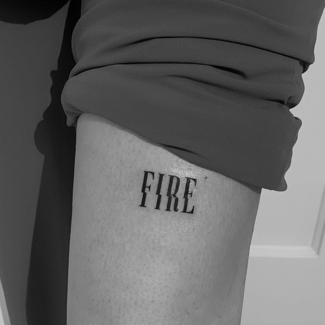 This firefighter tattoo features the word 'FIRE' in bold, stylized lettering.