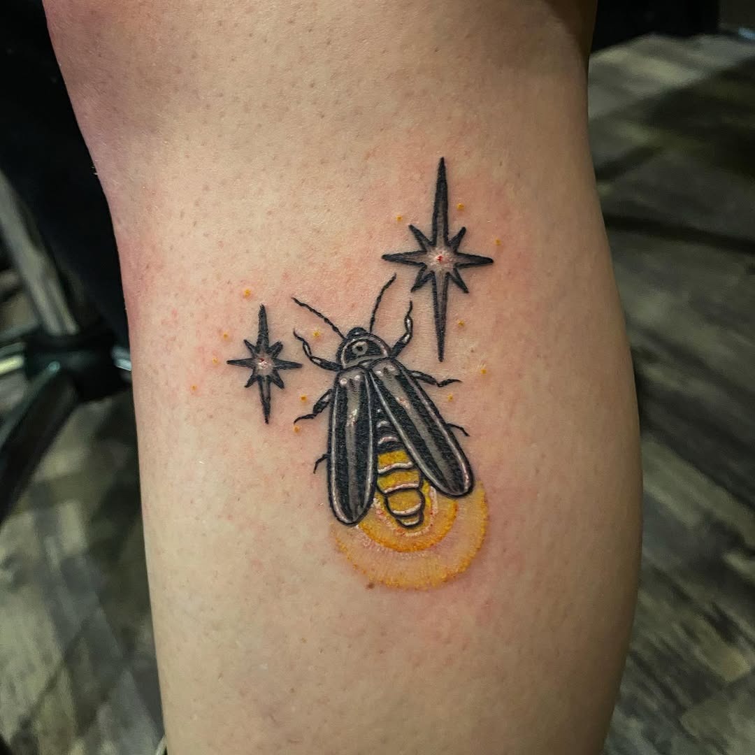 This enchanting firefly tattoo showcases a beautifully detailed insect surrounded by radiant stars.