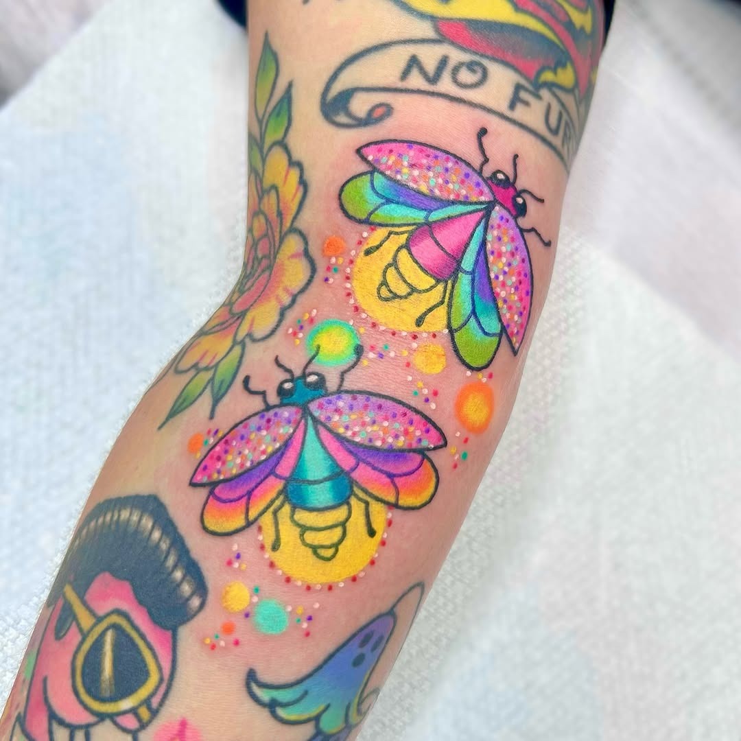 This tattoo showcases fireflies in bright pastels, creating a lively effect on the skin.