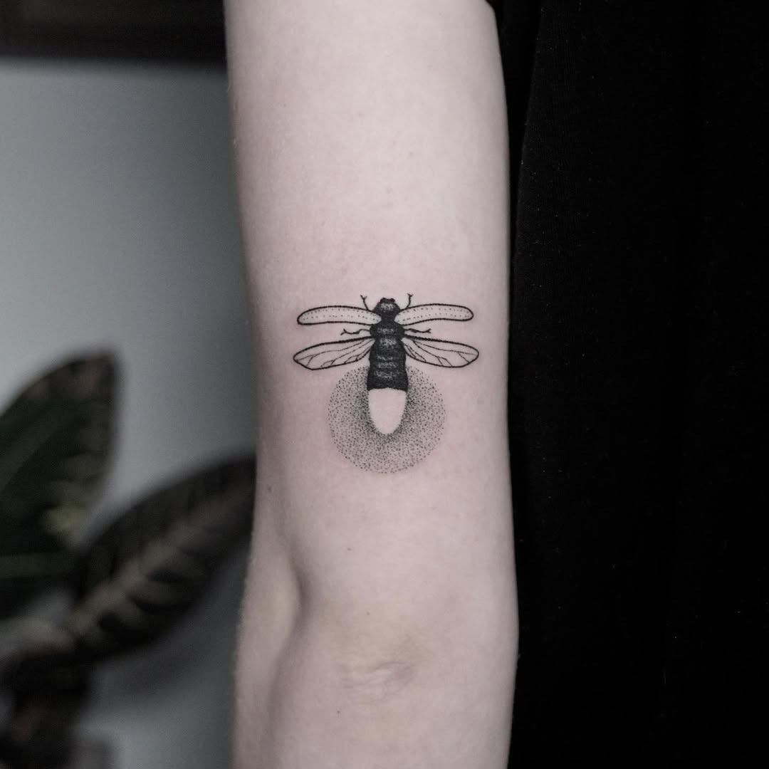 This unique tattoo features a beautifully detailed firefly in black line art.