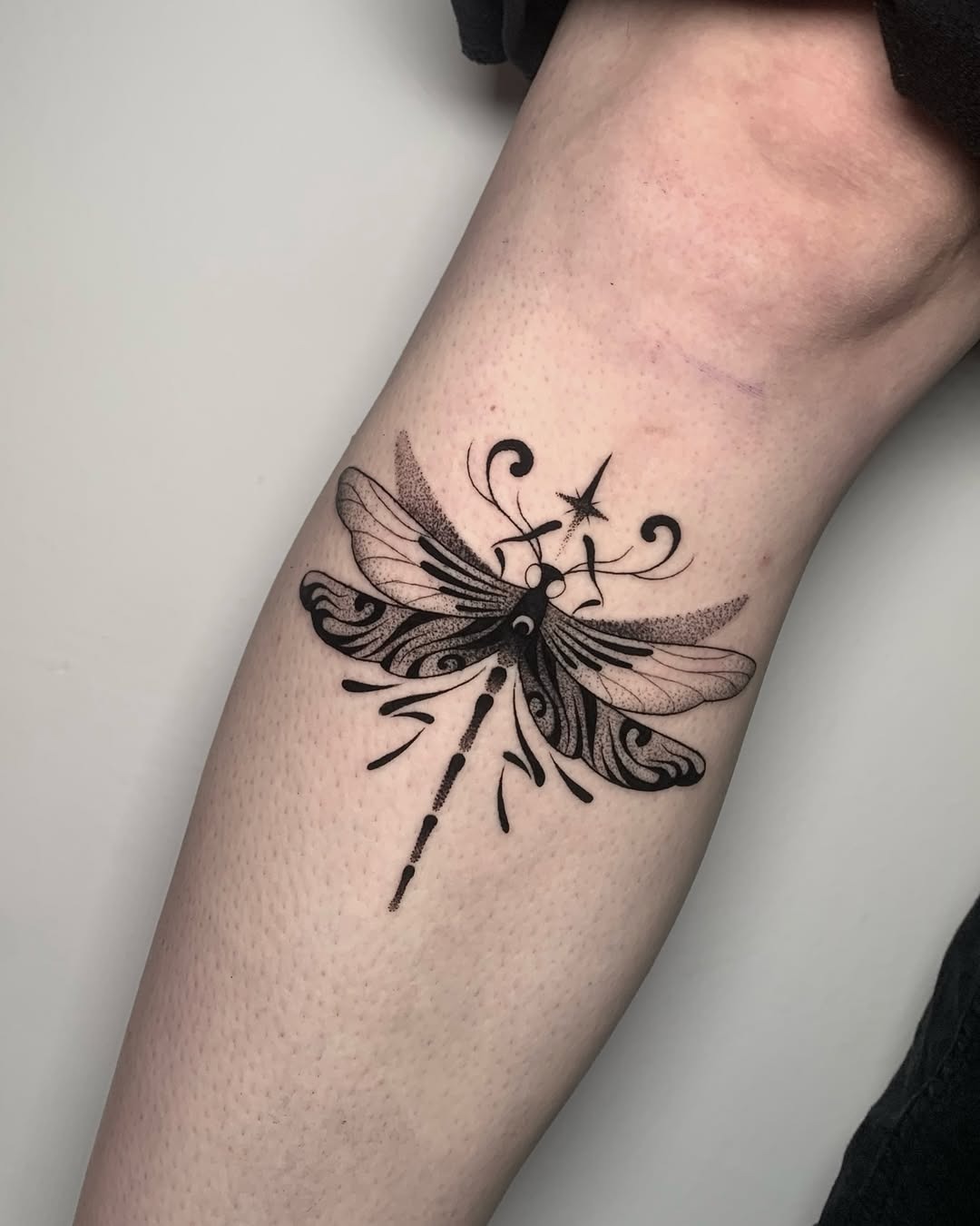 This captivating firefly tattoo features delicate linework and stunning black ink shading.