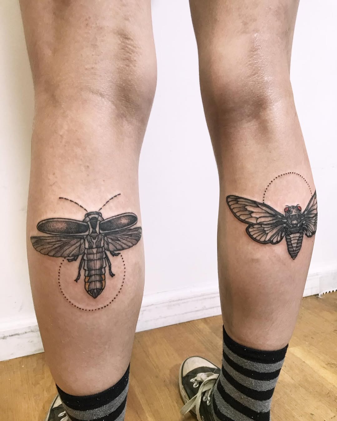 These stunning firefly tattoos feature intricate black line art, elegantly placed on the knees.