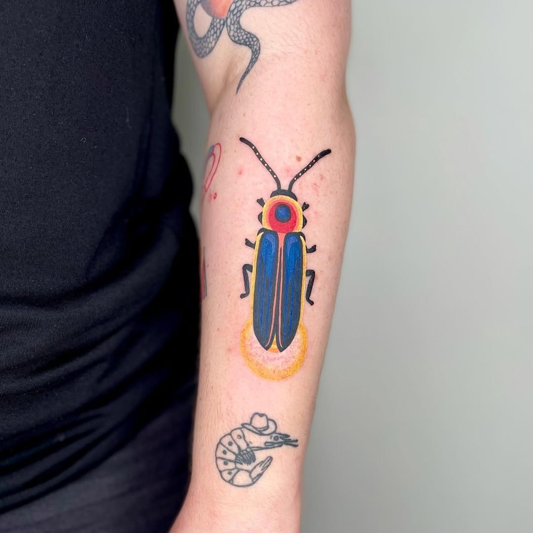 This colorful firefly tattoo features a vivid design with striking blues and reds.