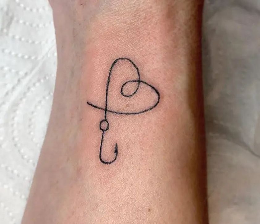 Simple Heart Fishing Hook Tattoo, a tattoo design rendered in delicate fine-line for the arm.