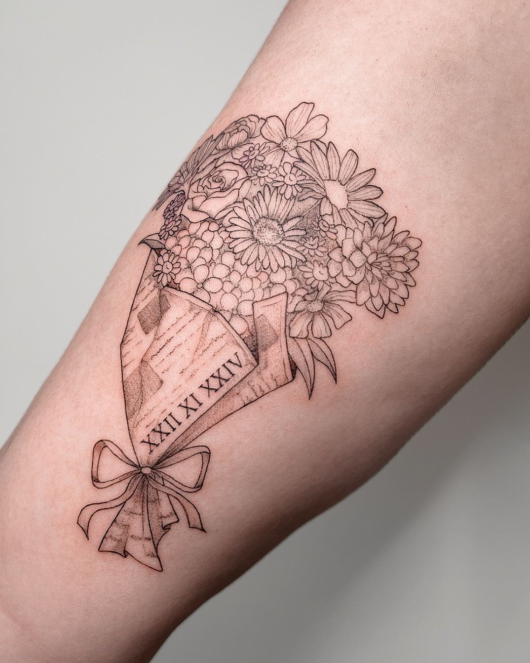 Vintage Paper-Wrapped Bouquet With Roman Numeral Detail, a tattoo design rendered in clean detailed linework.