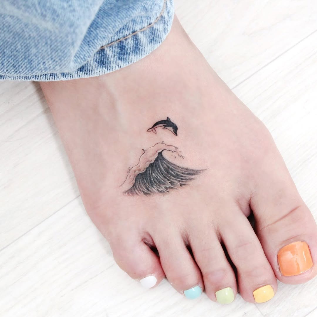 Graceful dolphin swimming over ocean waves tattoo Tattoo Design