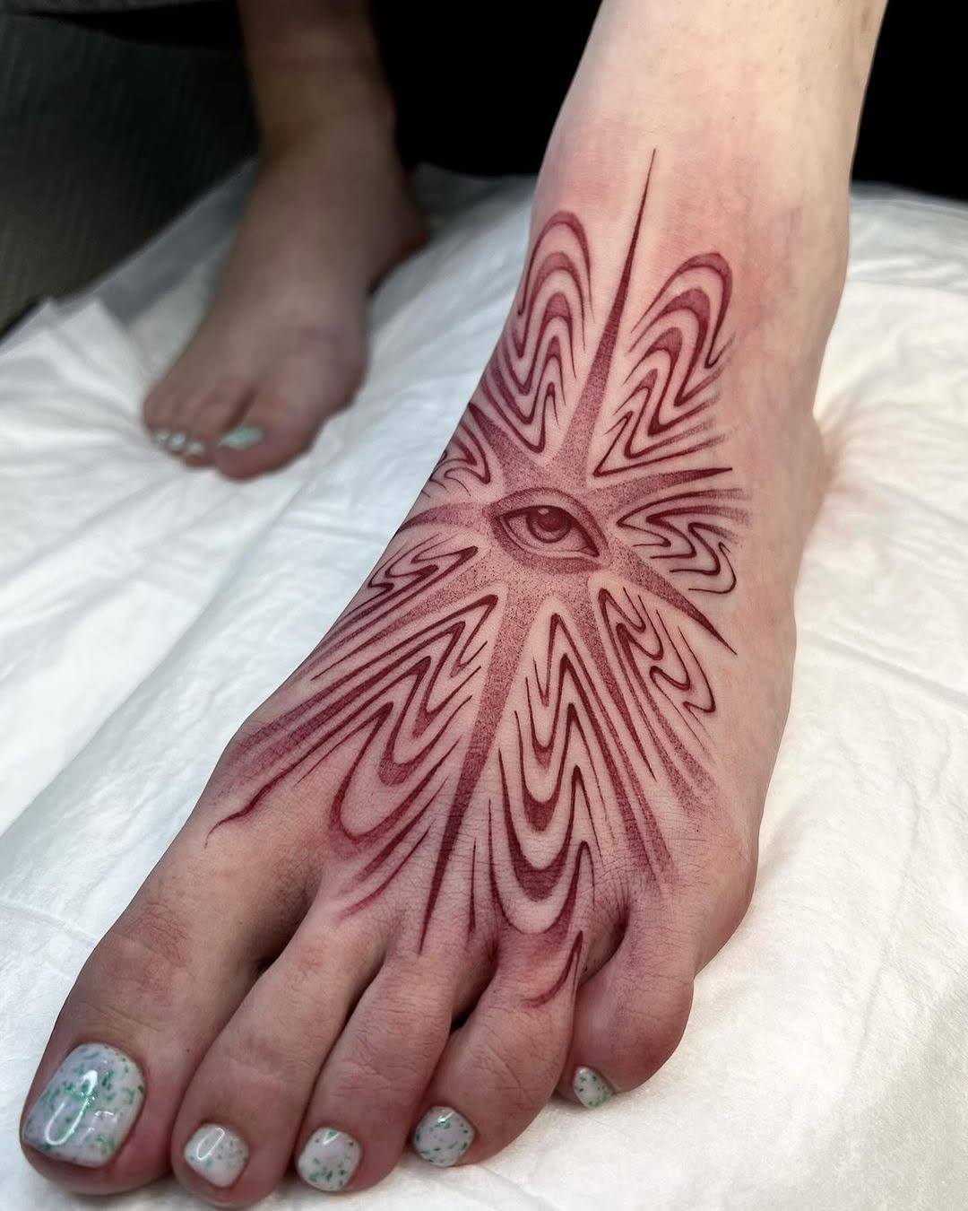 Intricate Eye Design Foot Tattoo in Red Ink Tattoo Design