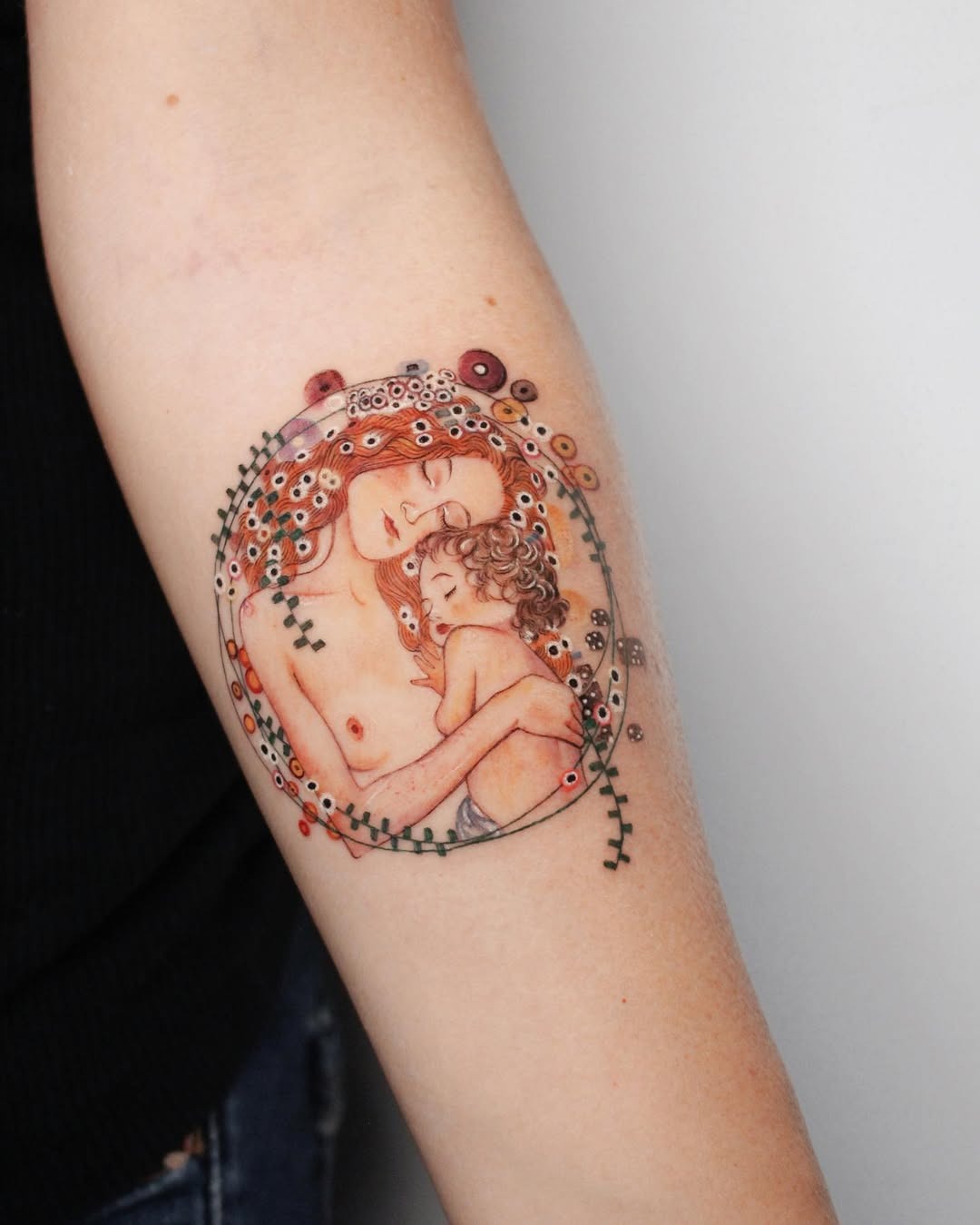 This forearm tattoo beautifully depicts a tender moment between a mother and child, enveloped in intricate floral designs.