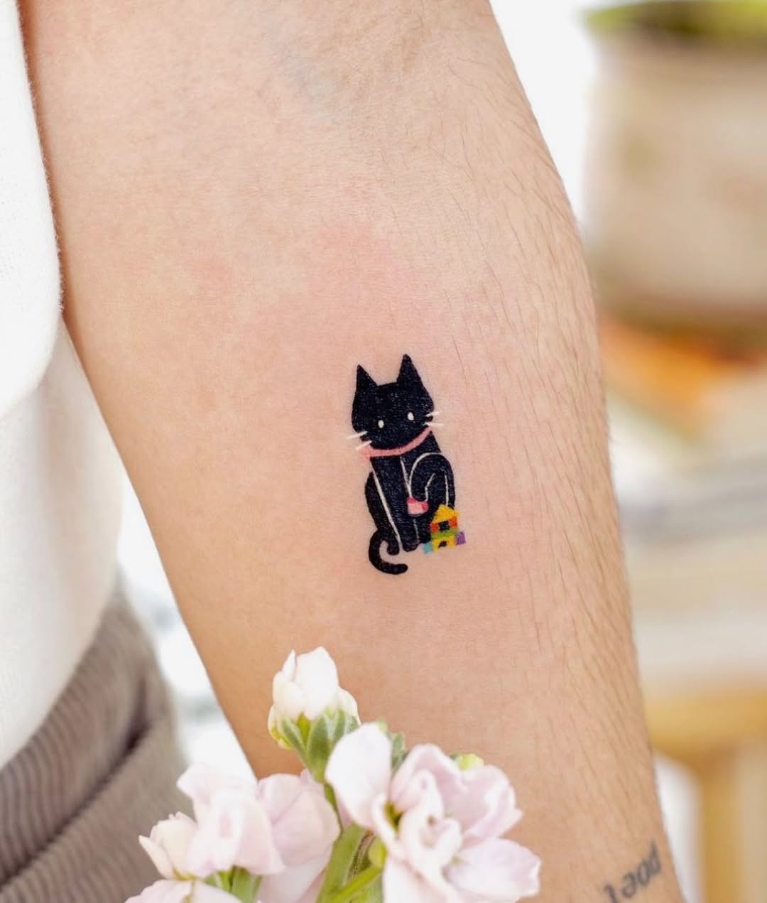 This forearm tattoo features a playful black cat, showing its artistic detail and whimsical essence.