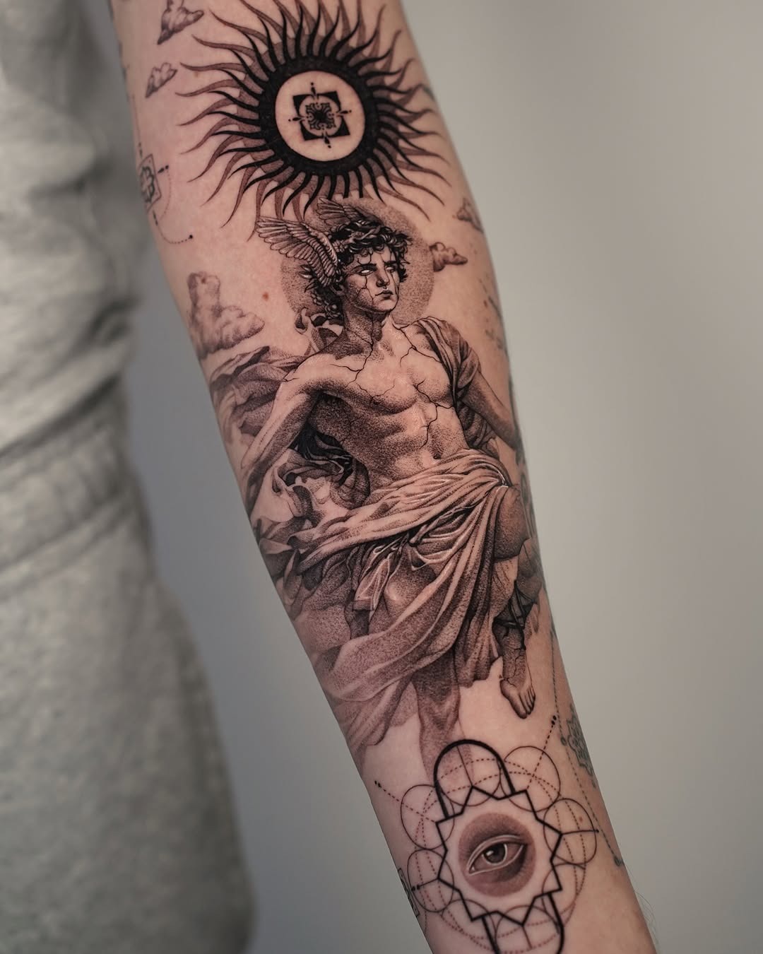 This forearm tattoo showcases stunning classical Greek artistry, featuring a muscular figure draped in flowing fabric.