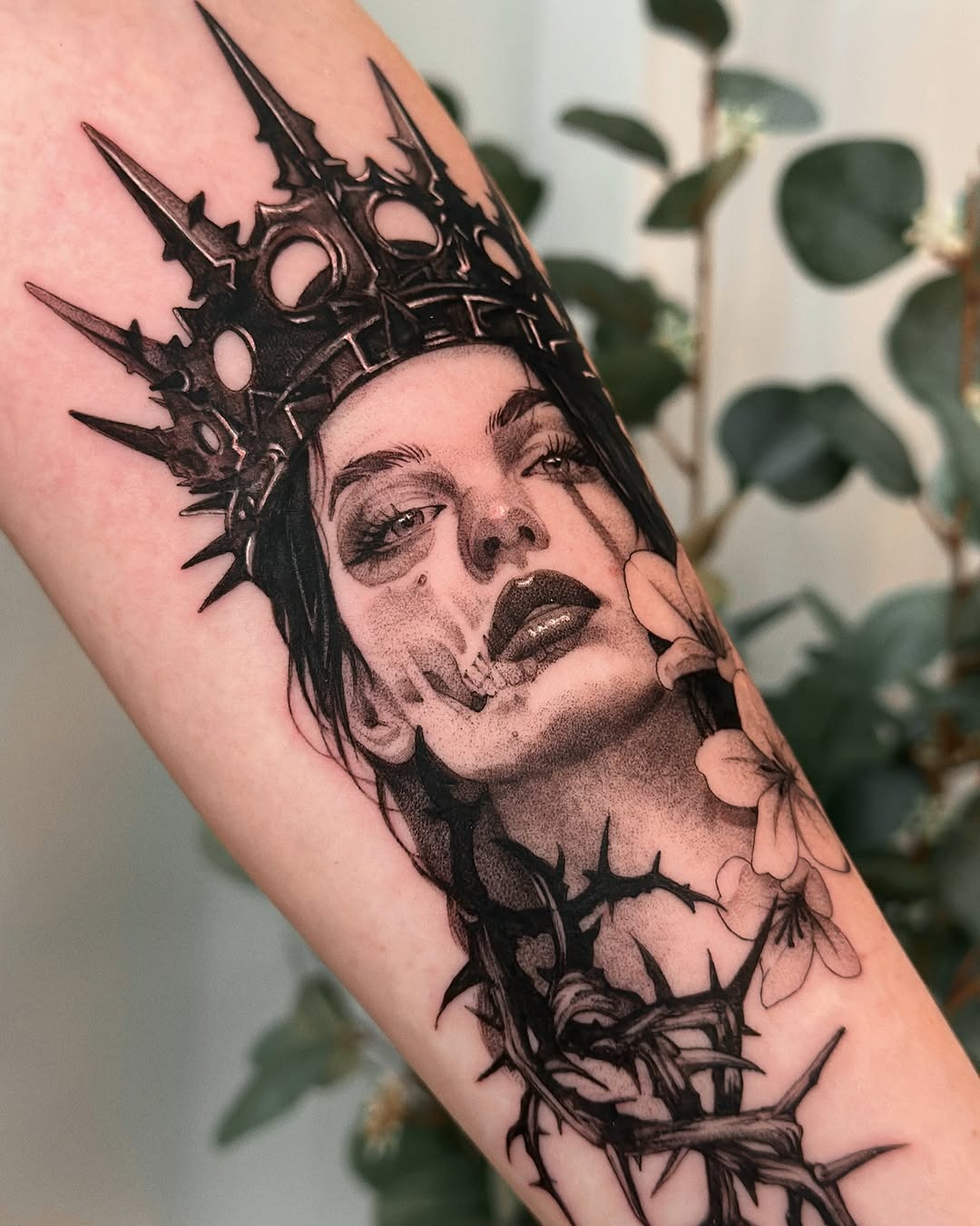 This forearm tattoo features a captivating design of a crowned skull, beautifully intertwined with roses.