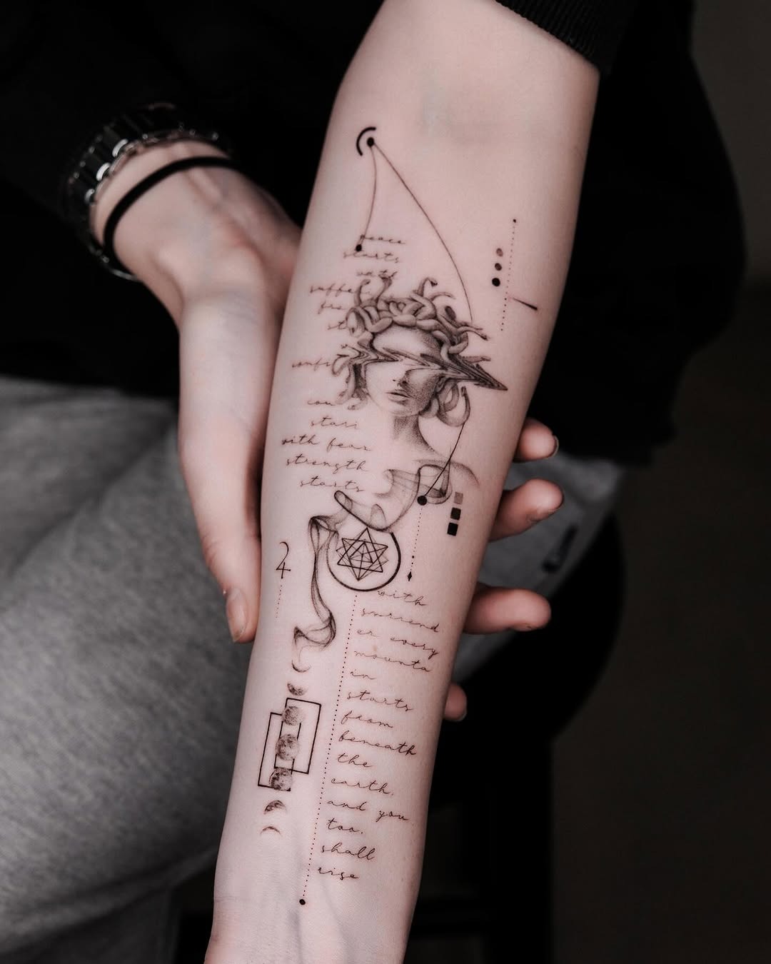 This forearm tattoo features a stunning blend of artistic elements, including a serene female figure surrounded by intricate geometric shapes and delicate script.