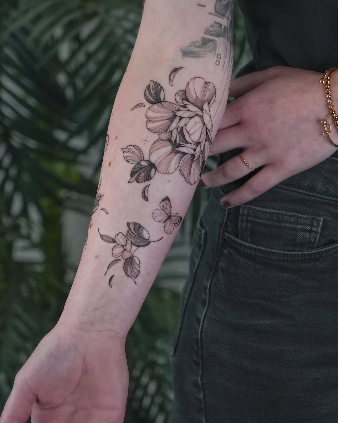 This forearm tattoo showcases beautiful flowers intertwined with delicate butterflies.