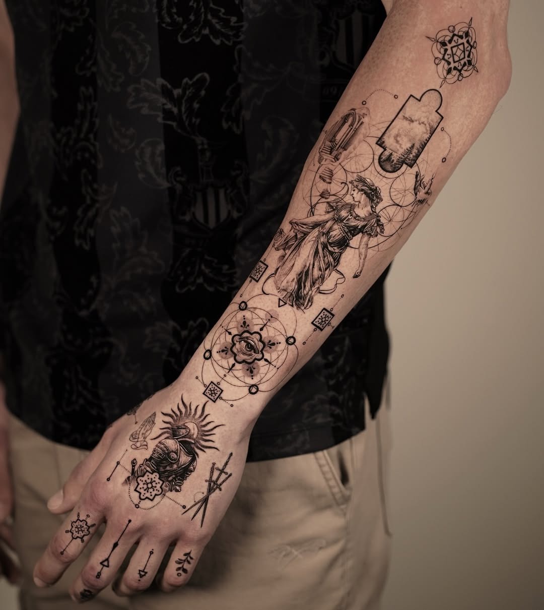 This forearm tattoo features a blend of intricate black ink designs, showing both religious and abstract elements.