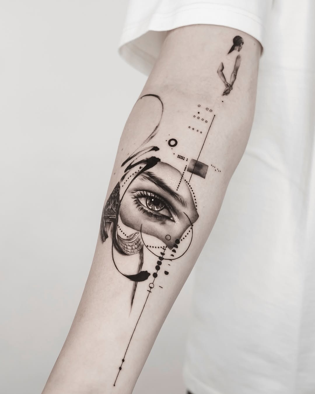 This forearm tattoo features an intricately designed eye intertwined with geometric elements.