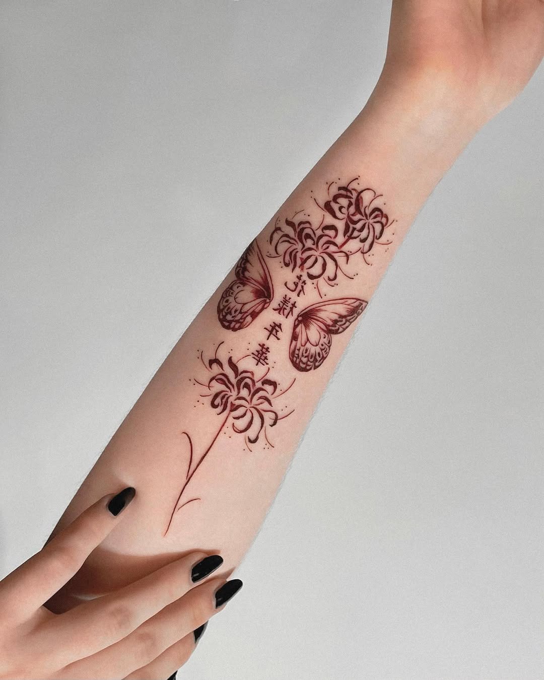 This forearm tattoo features intricate designs of butterflies and flowers in red ink.