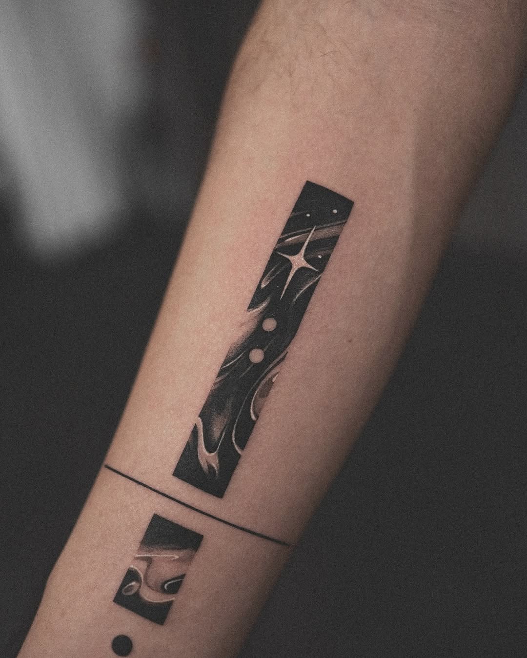This forearm tattoo features sleek, abstract designs in black and gray.