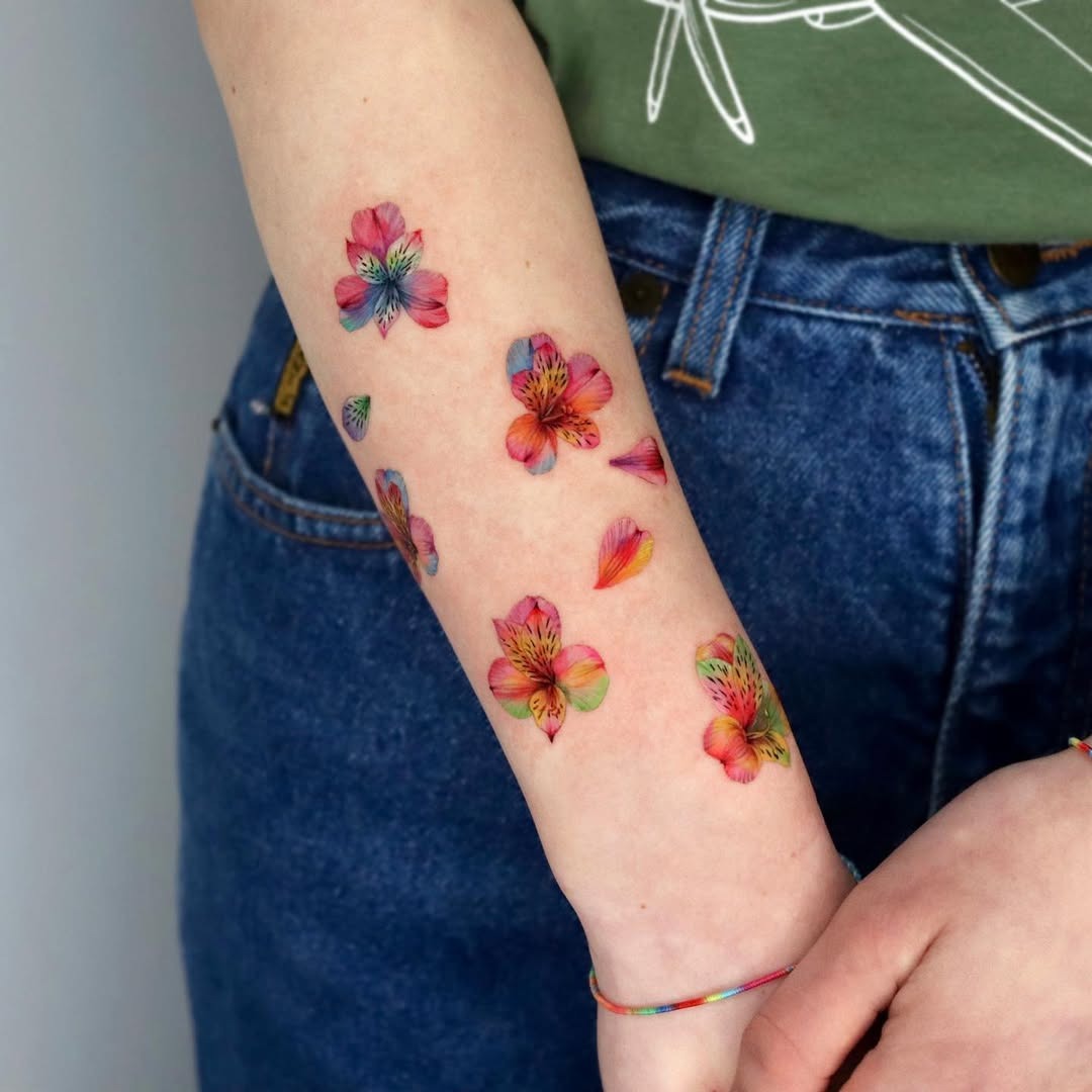 This forearm tattoo showcases a stunning array of colorful flowers, beautifully designed to create a lively aesthetic.