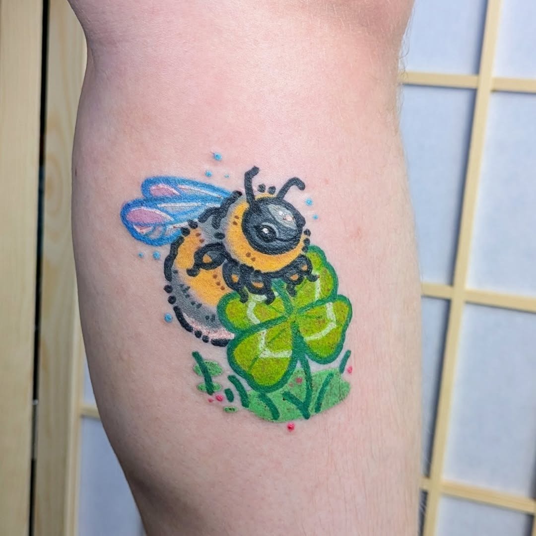 Colorful bee atop a four-leaf clover tattoo. Tattoo Design