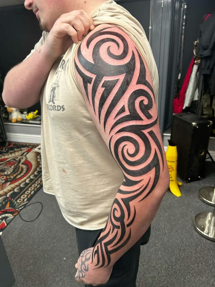 Bold Black Tribal Sleeve with Swirl Motifs Tattoo Design