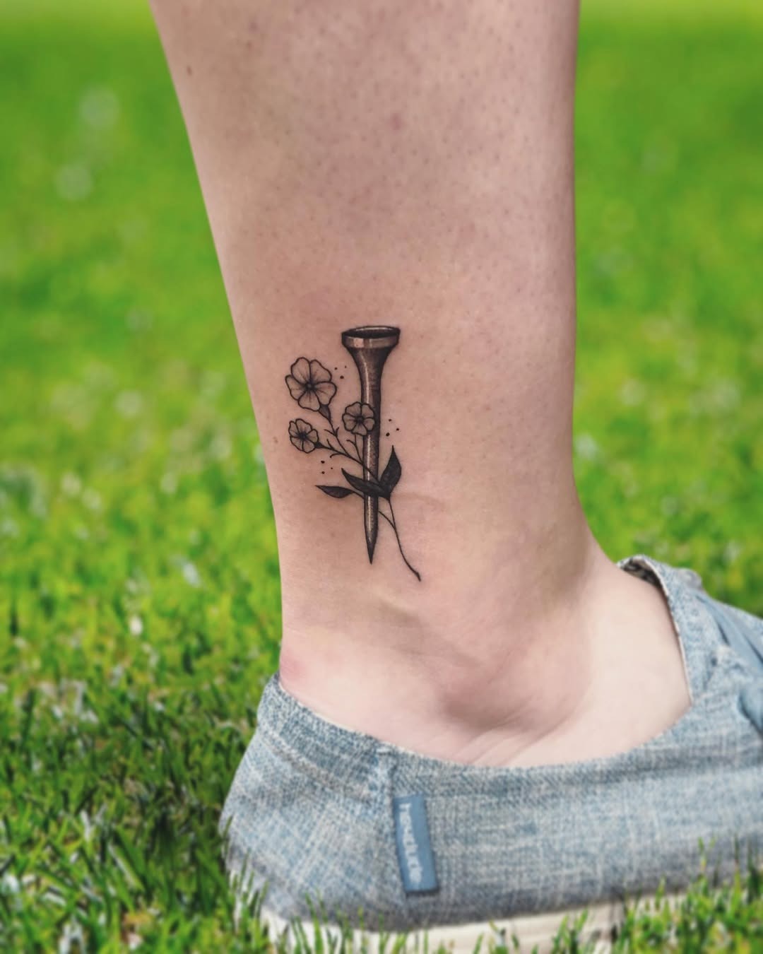 Elegant golf tee adorned with floral elements Tattoo Design
